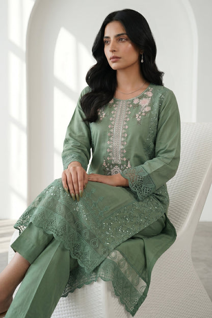 Woman wearing a green embroidered dress sitting on a white chair.